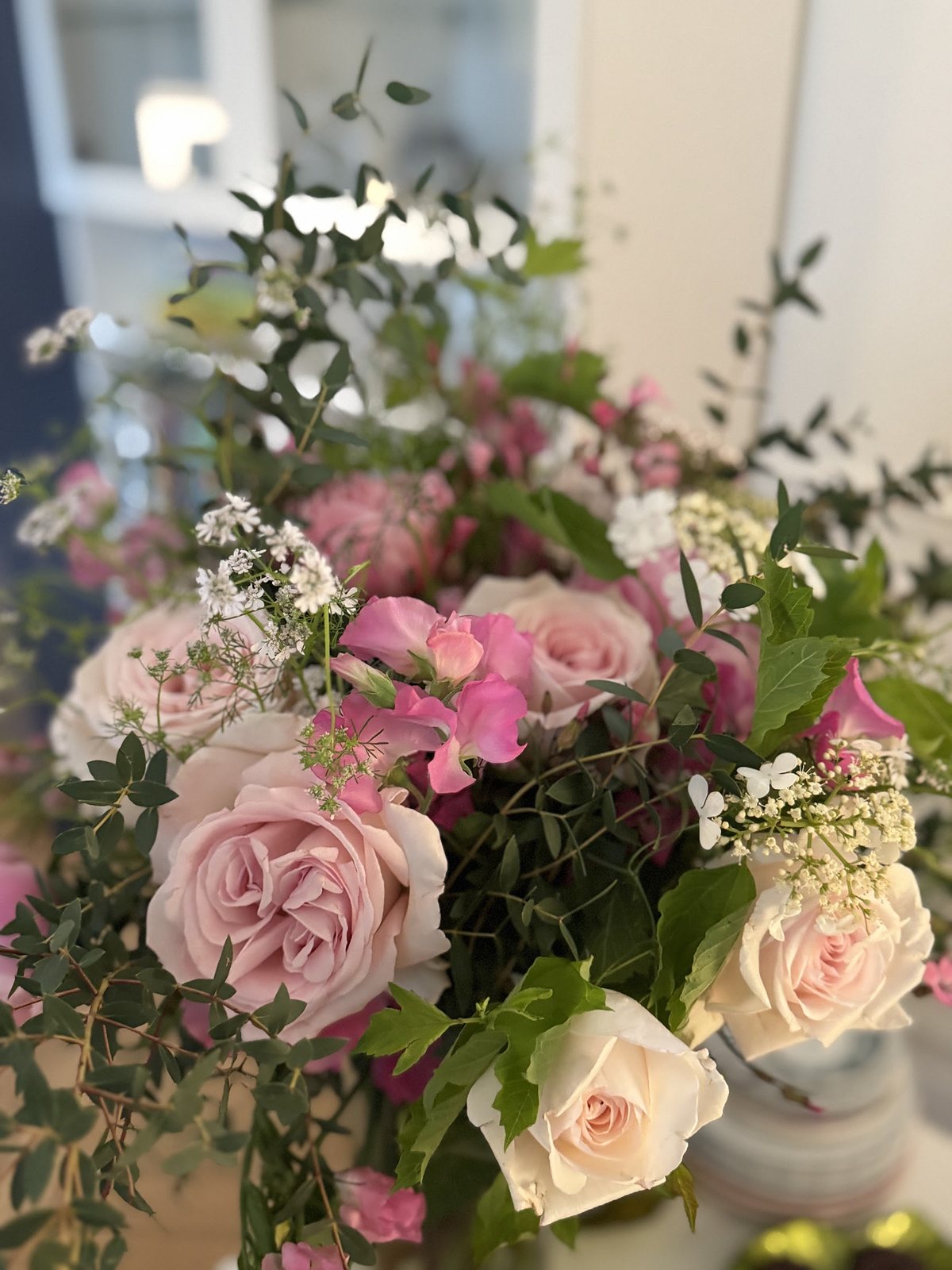 Bouquet de roses pâles et d’eucalyptus dans un vase blanc