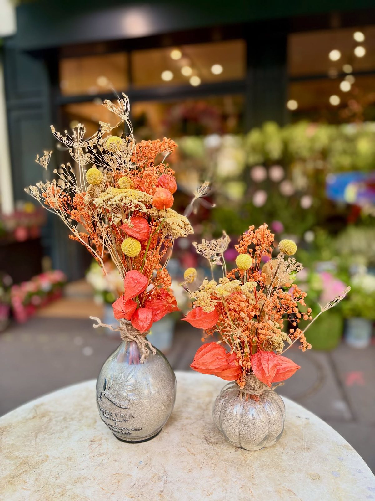 Deux vases de fleurs séchées orangées sur un guéridon de marbre